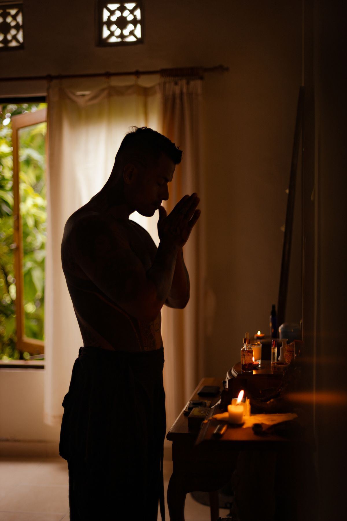Homem em silhueta meditando à luz de velas em ambiente contemplativo e espiritual