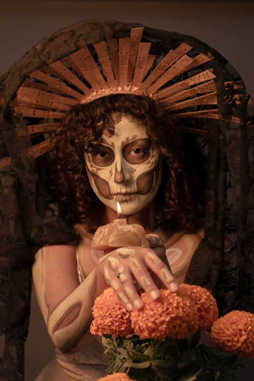 Free A woman with skull face paint holding a candle, symbolizing Day of the Dead. Stock Photo