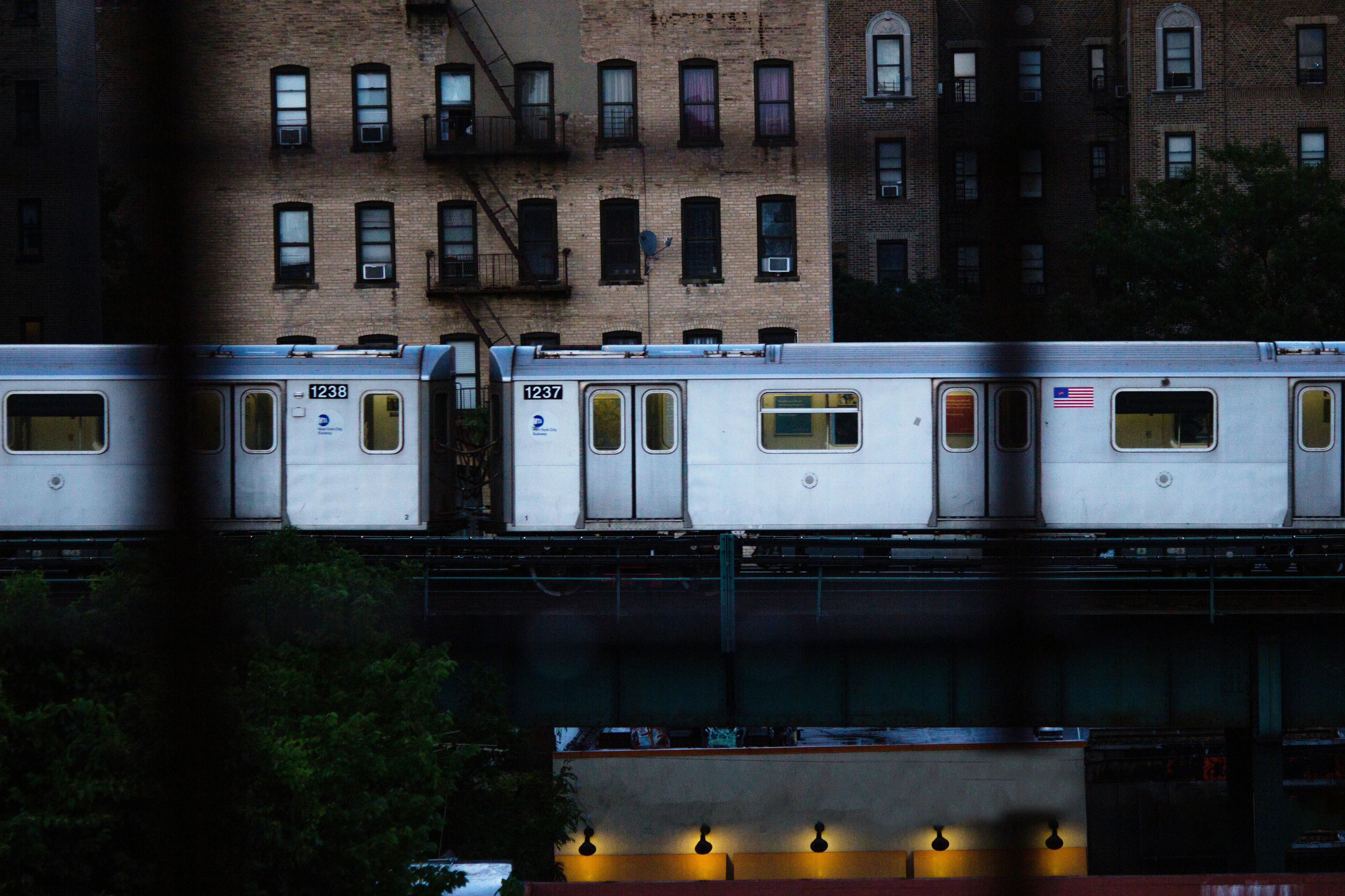 Free City subway train travels on elevated tracks past brick apartments during the day. Stock Photo