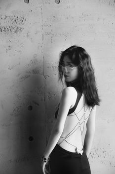 Black and white portrait of a woman in stylish attire against a textured wall.