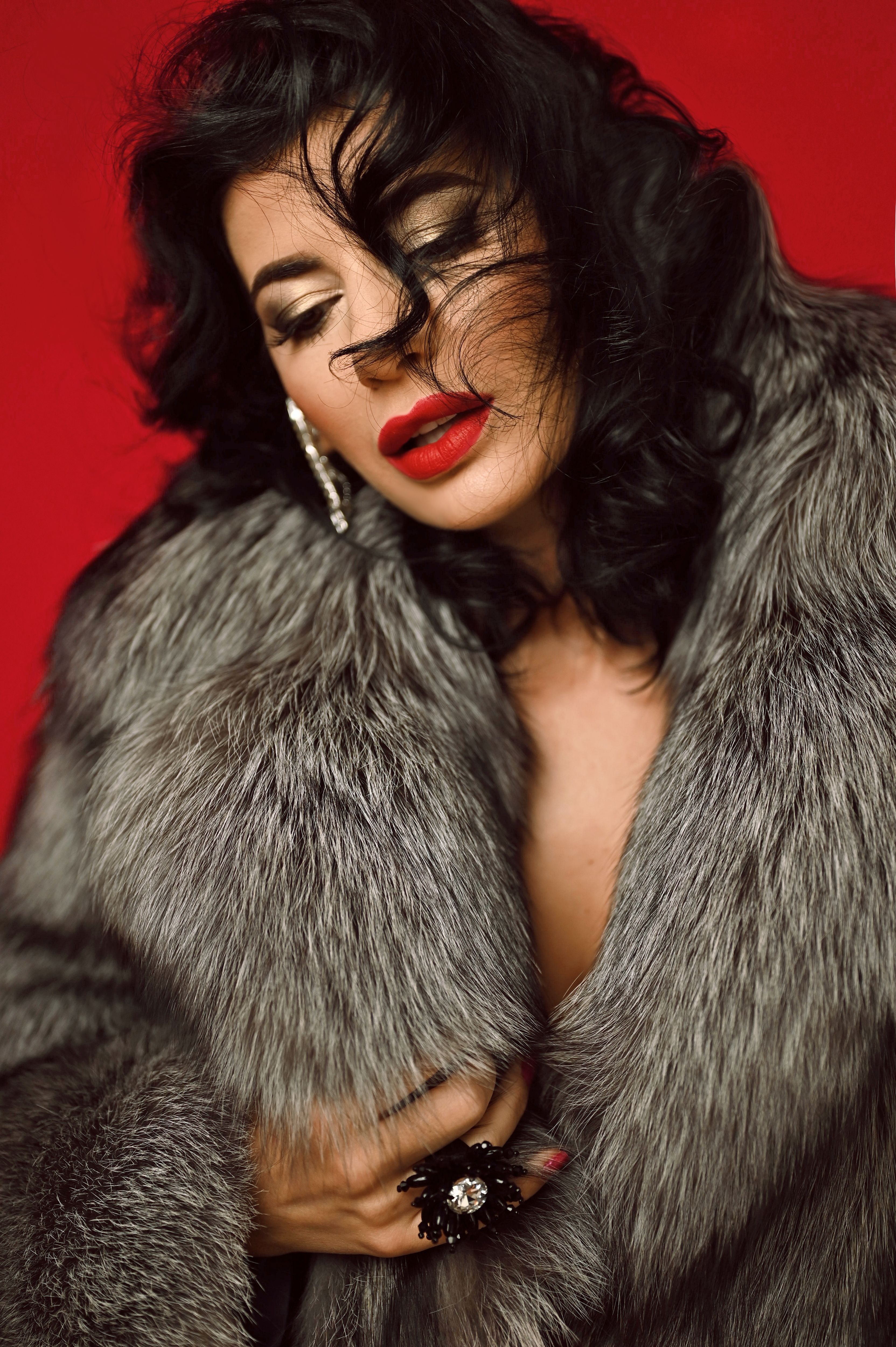 Glamorous portrait of a woman in a luxurious fur coat, showcasing red lipstick and jewelry.