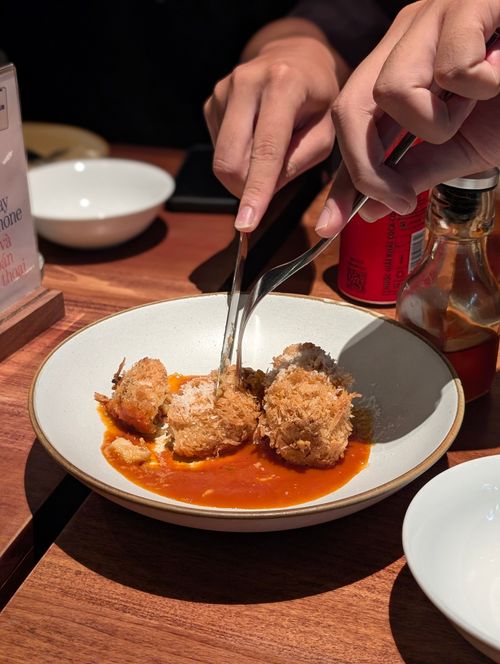 Free Close-up of hands serving crispy croquettes with sauce on a wooden table, creating a warm dining atmosphere. Stock Photo