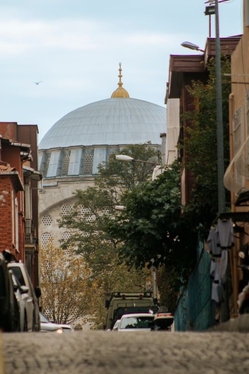 Free Scenic view of a historic mosque dome peeking above charming Istanbul street. Stock Photo