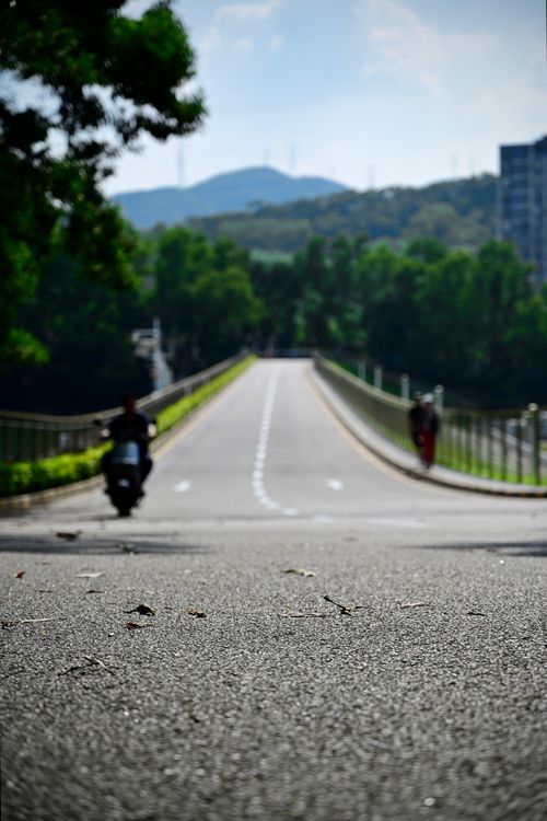 Free A scenic road with a motorbike and pedestrian on a sunny day. Stock Photo
