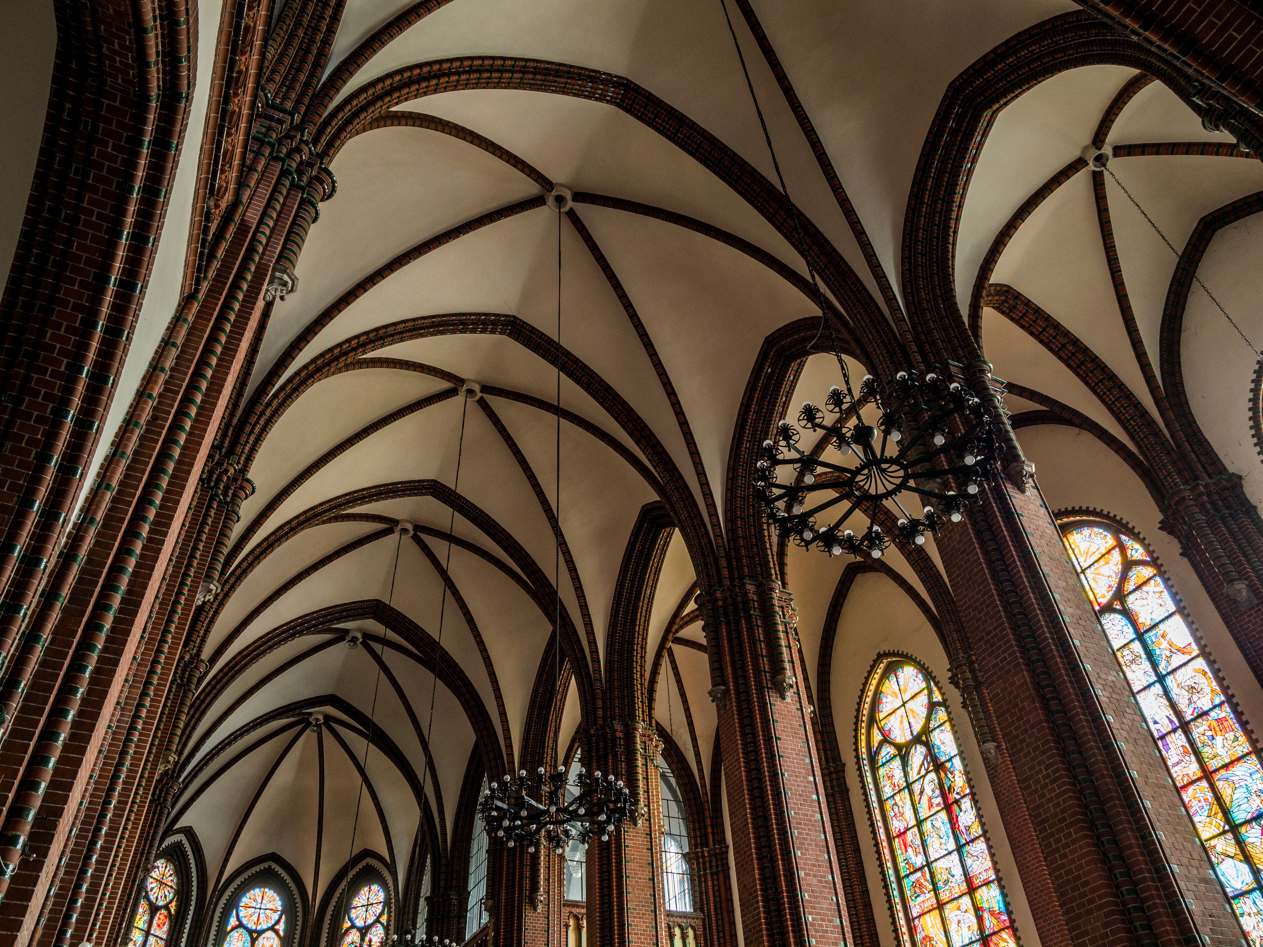 Interior view of a gothic cathedral featuring vaulted ceilings and colorful stained glass windows.