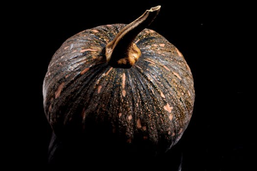 Close-up image of a pumpkin on a glossy black background, highlighting texture and colors.