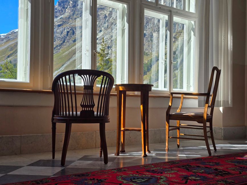 Sunlit room with elegant chairs overlooking a mountainous landscape, perfect for relaxing.