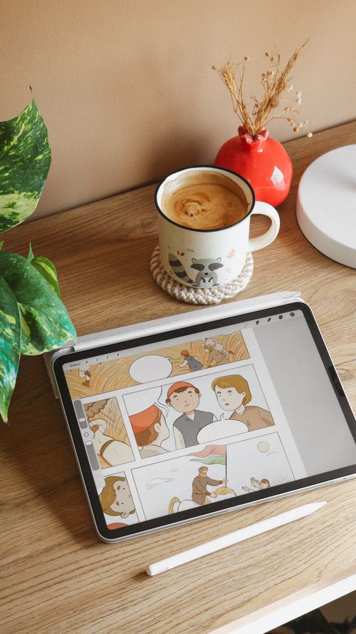 Free A cozy workspace featuring a tablet with digital art, a coffee cup, and plant, embodying creativity and comfort. Stock Photo