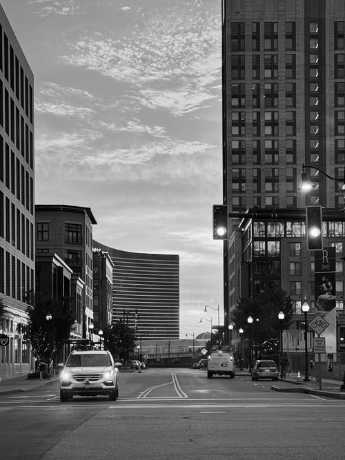 Free A black and white photo of a city street at twilight with illuminated buildings. Stock Photo