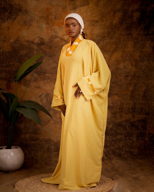 Free Woman in elegant robe with headscarf stands against a textured background, striking a serene pose. Stock Photo