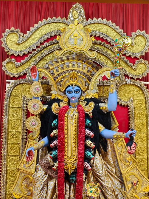 Free Colorful and detailed idol of Goddess Kali adorned in intricate gold with vibrant red background. Stock Photo