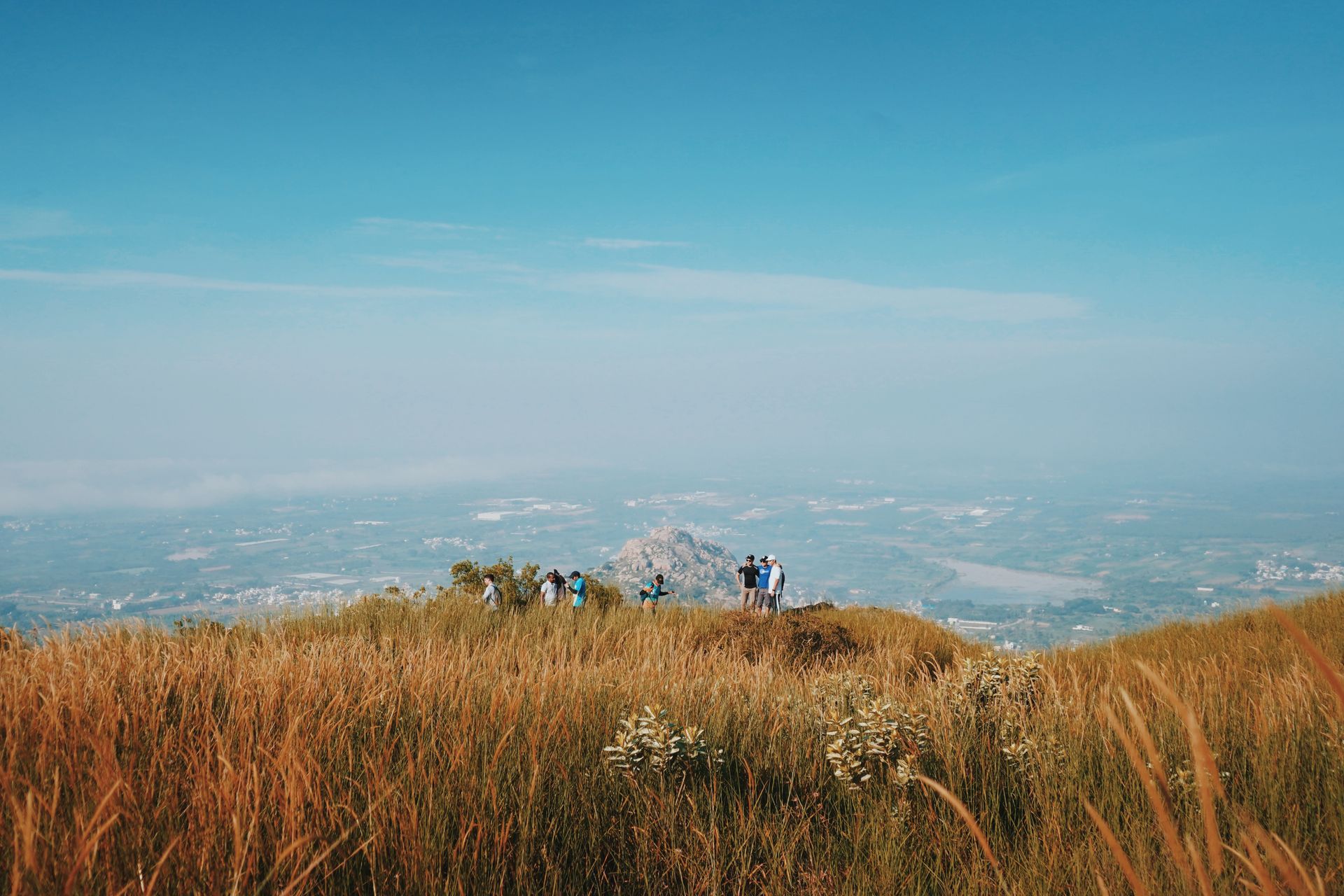 A group of hikers enjoying the scenic view from a mountain summit under a clear blue sky.