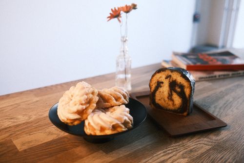 Free A cozy setup of pastries and a slice of coffee cake on a rustic table with a vase and magazines. Stock Photo