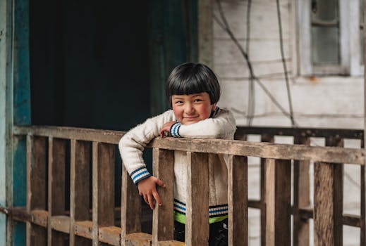 Cheerful child leaning on a wooden balcony in Gangtok, Sikkim, India.