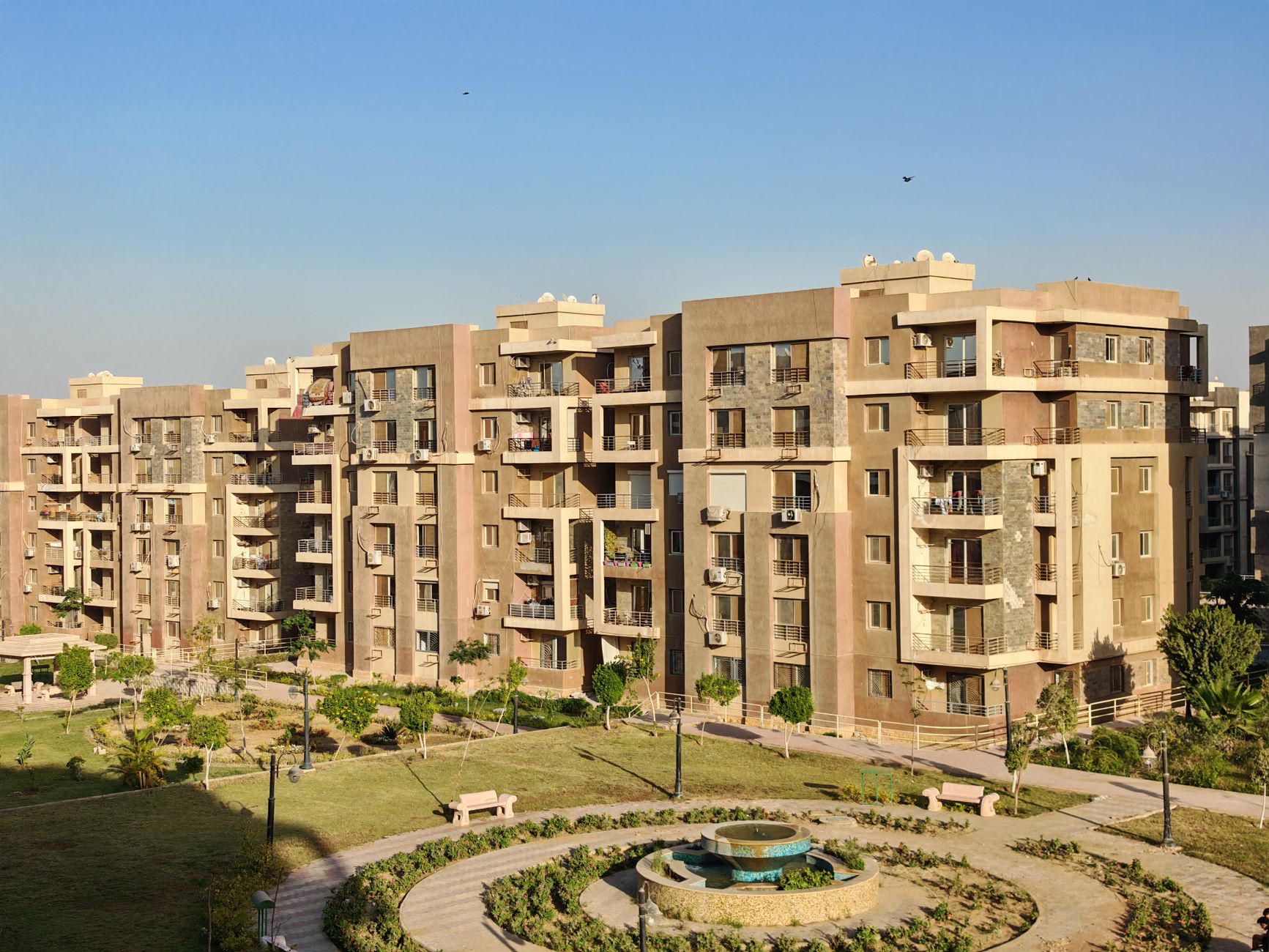 Sunny urban scene of modern apartment buildings and landscaped gardens.