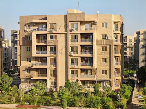 A modern apartment complex with greenery in a sunny urban environment.