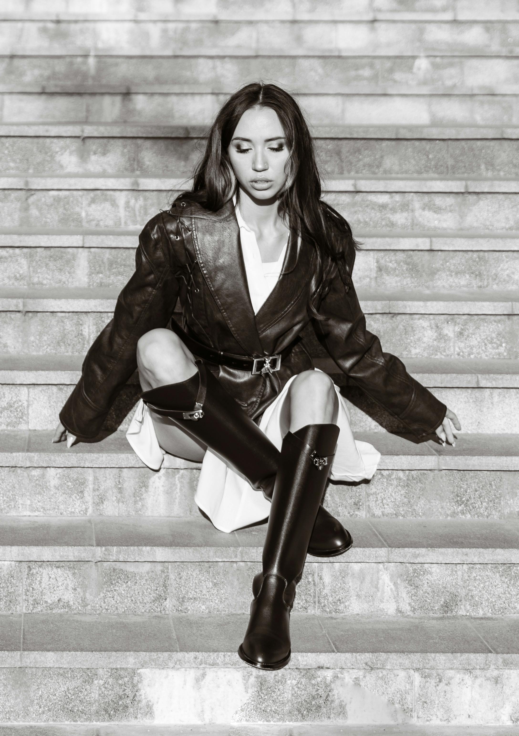 Free Woman in stylish leather outfit sitting on stairs, black and white photo. Stock Photo