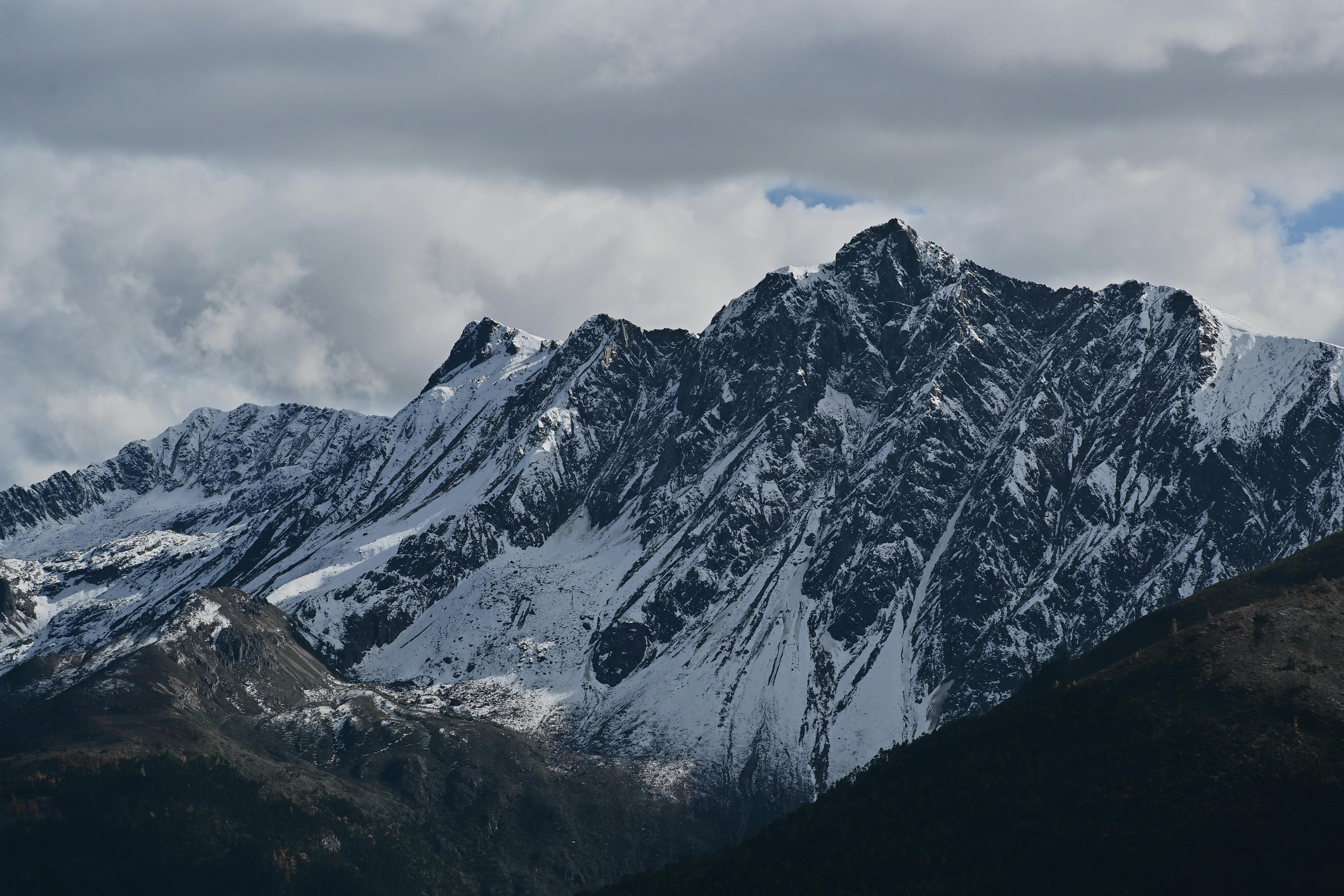 Stunning view of snow-covered mountain peaks with dramatic clouds overhead.