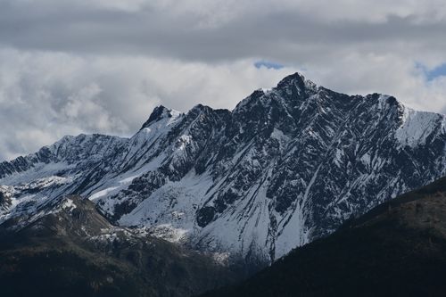 Free Stunning view of snow-covered mountain peaks with dramatic clouds overhead. Stock Photo