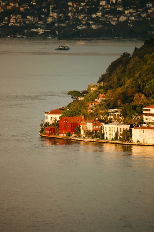 Free Charming view of Istanbul's Bosphorus waterfront with vibrant homes and lush hills at sunset. Stock Photo
