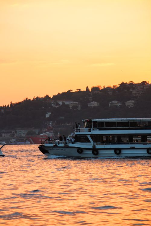 Free A passenger boat sails through the golden waters of the Bosphorus at sunset. Stock Photo