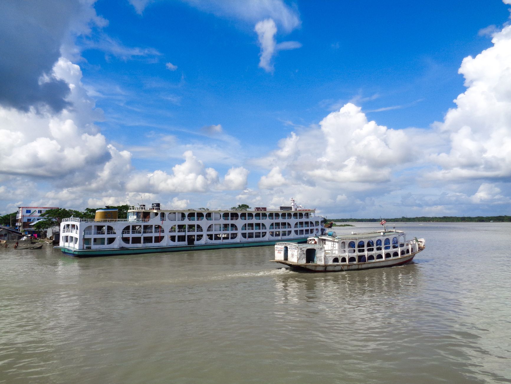 Two ferries sailing on the Kirtankhola River in Barishal, under a clear blue sky.