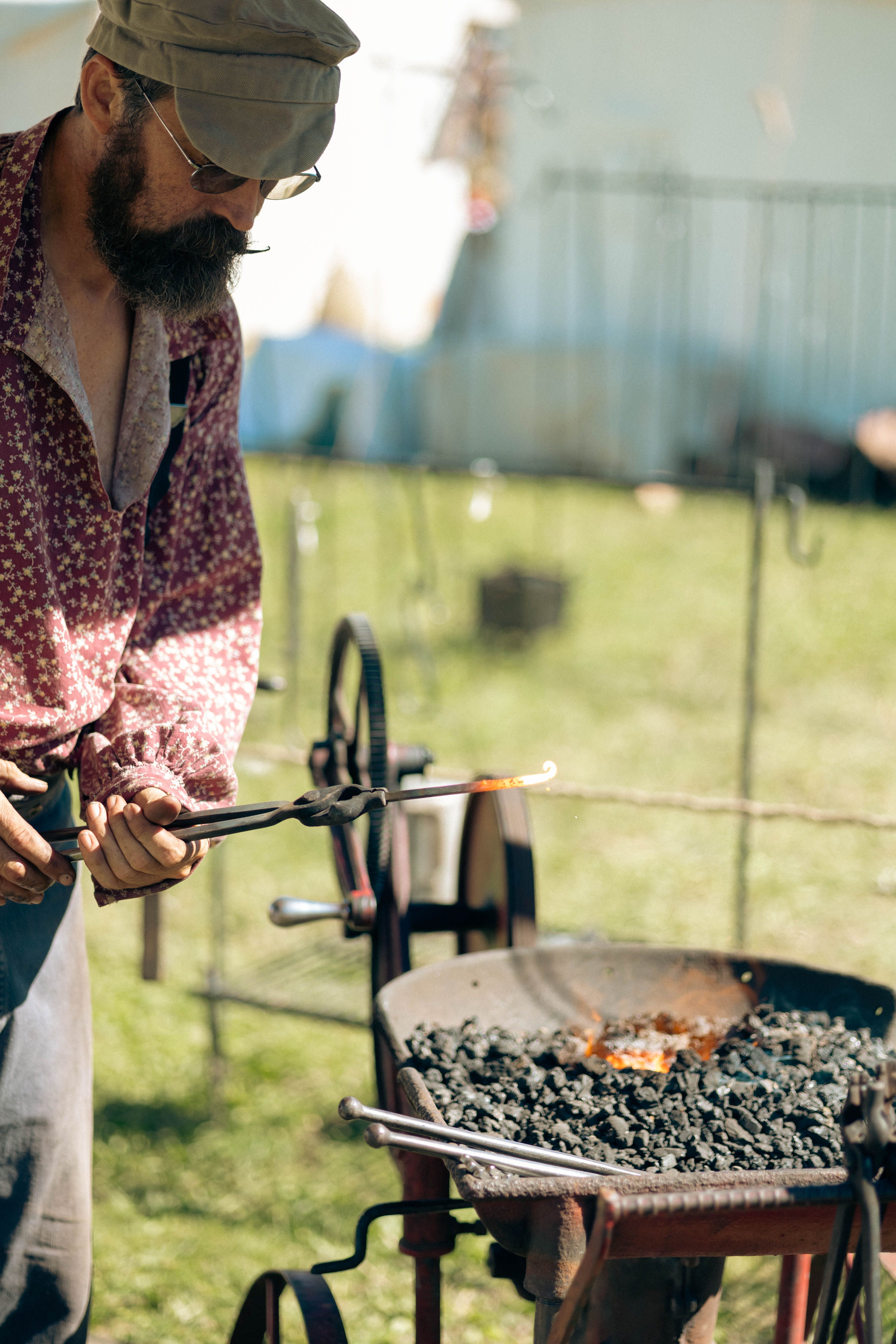 A blacksmith working at an outdoor forge, shaping metal using traditional techniques.