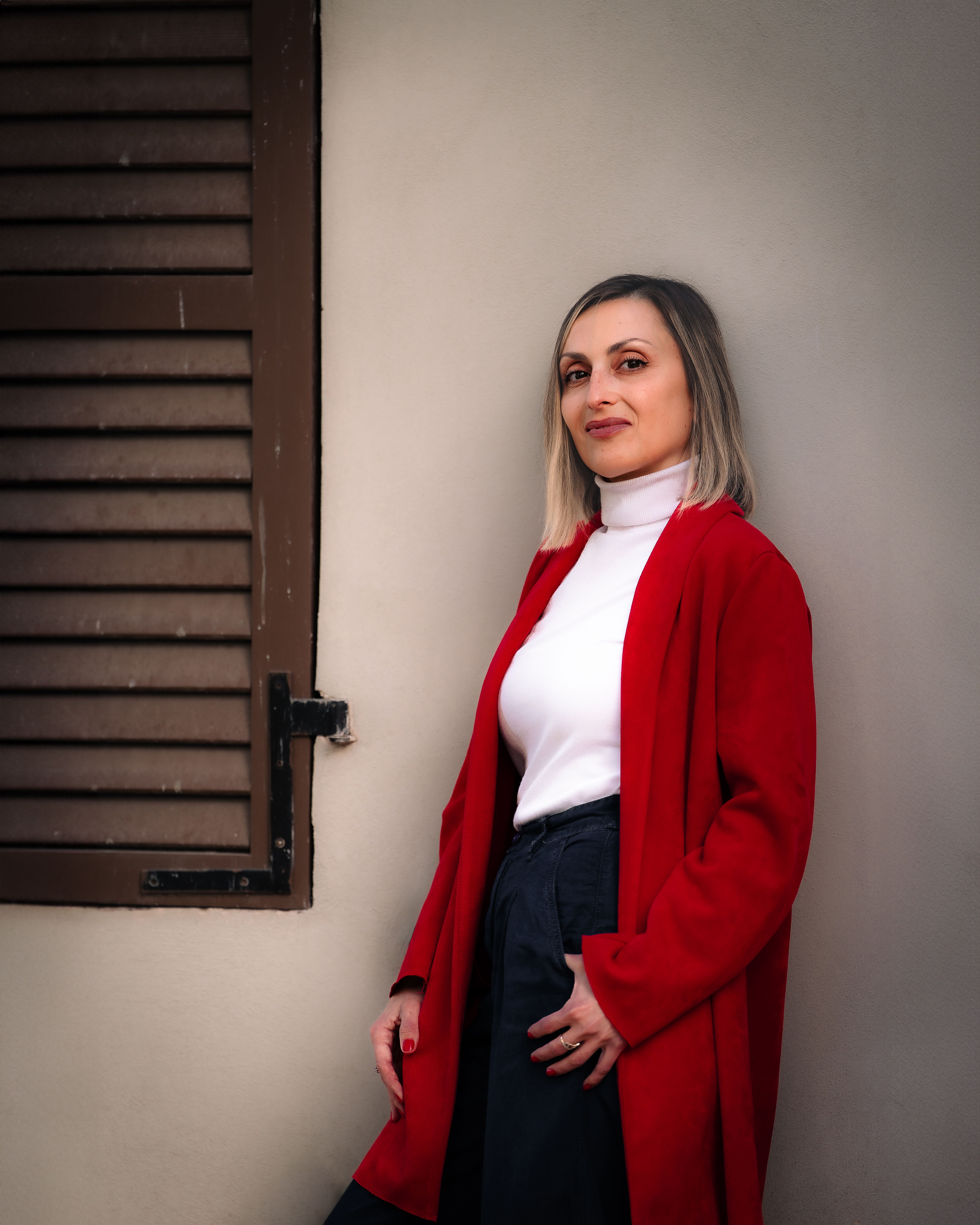 Woman in Red Coat Leaning Against Wall · Free Stock Photo