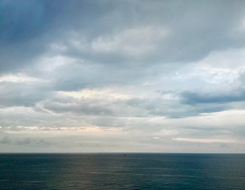 Free A calming view of the ocean beneath a vast, cloudy sky, captured during daytime. Stock Photo