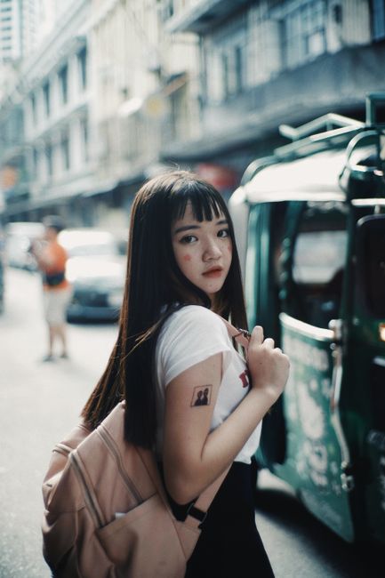 Young woman walking with backpack through lively city street, capturing travel vibe.