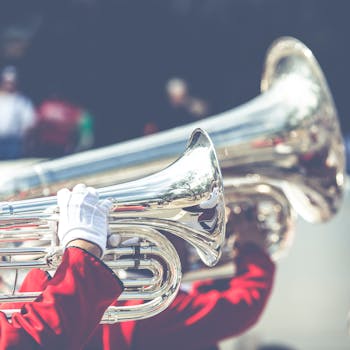 Musicians play brass instruments in a lively outdoor parade, with reflections on shiny surfaces.