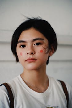 柔和的灯光下，一位短发、身着白衬衫的女子正在化妆的特写肖像