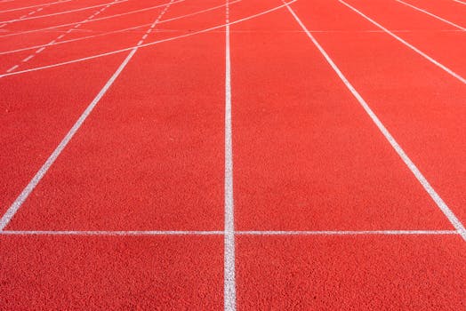 Vibrant red athletics track with distinct white lines creating dynamic patterns.