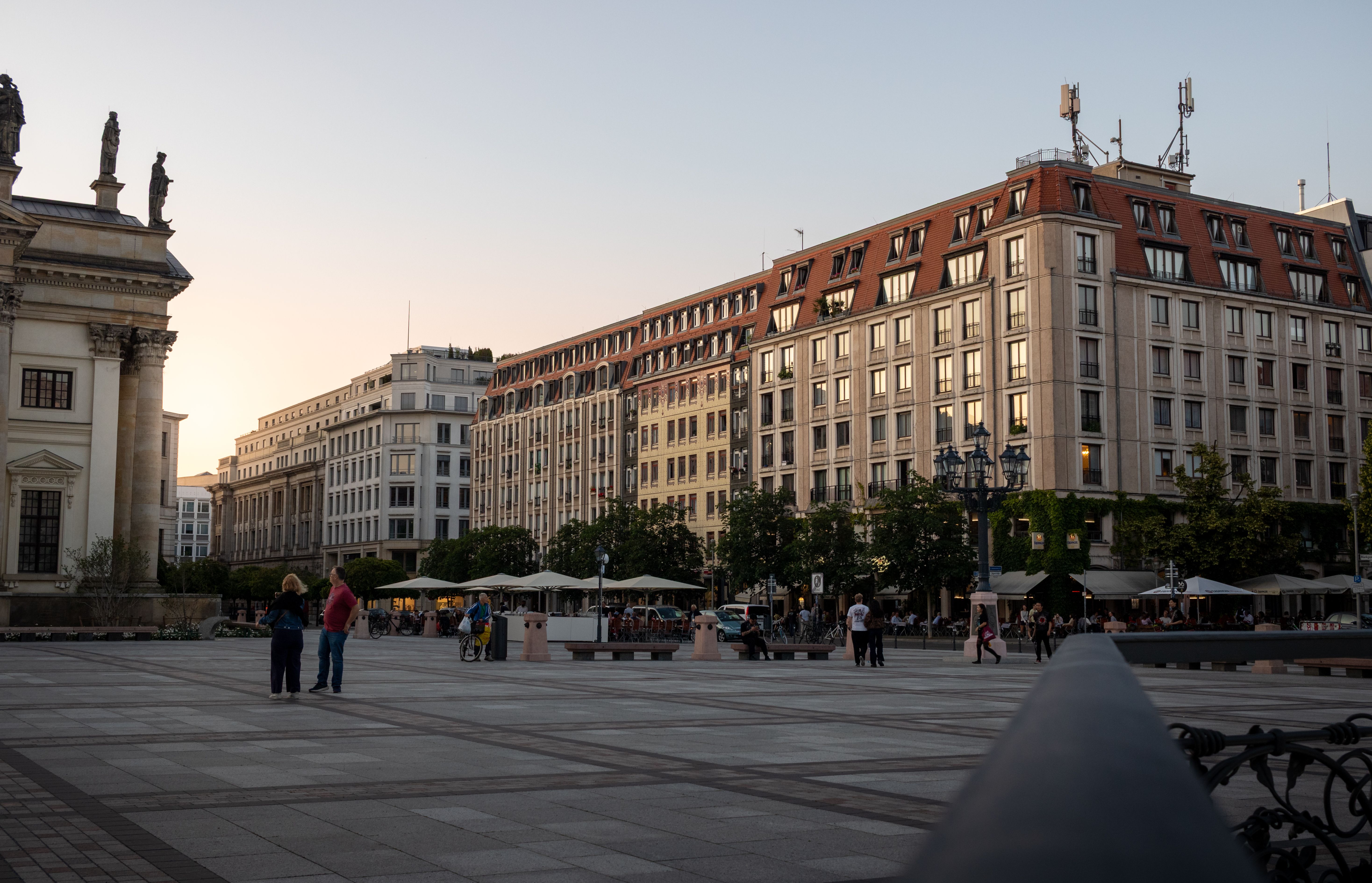 Stunning view of historic architecture in Berlin at sunset with people walking by.