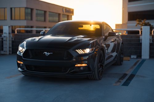 Free Elegant black sports car in urban parking, captured beautifully at sunset. Stock Photo