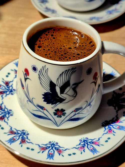 Free Beautifully frothy Turkish coffee served in an intricately designed cup with a bird motif. Stock Photo