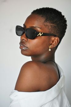 Portrait of a confident black woman wearing sunglasses, showcasing elegant style and natural beauty.