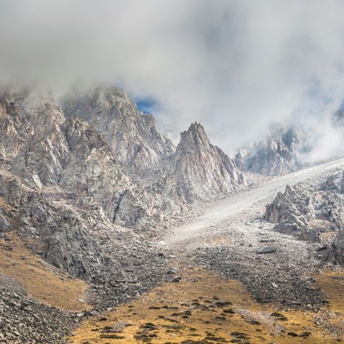 Free Majestic rocky mountain peaks shrouded in clouds on a bright day, showcasing nature's grandeur. Stock Photo