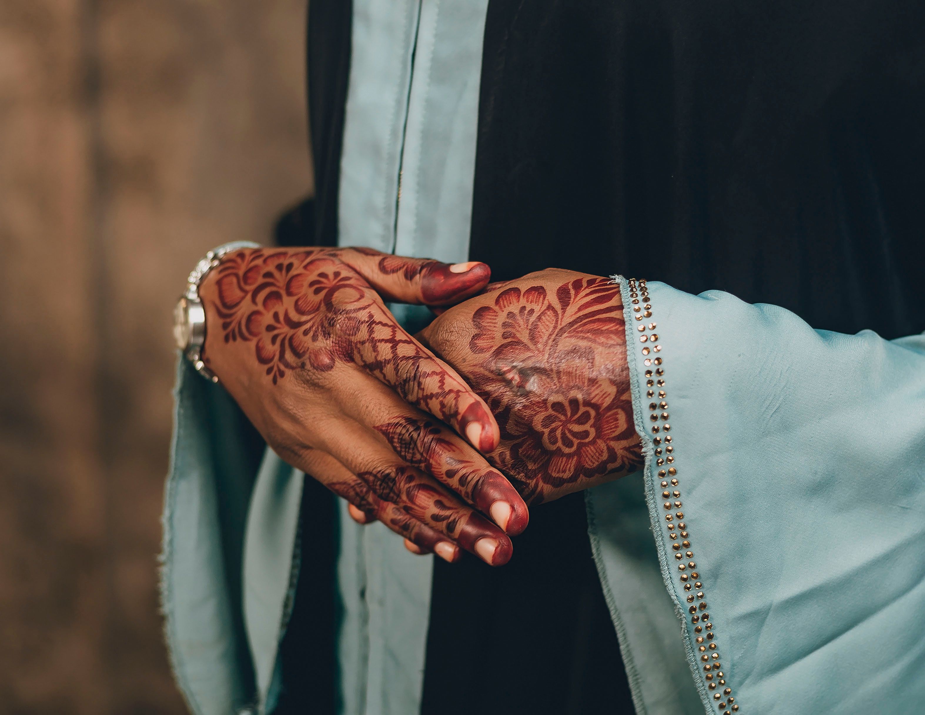 Close-up of intricate henna designs on hands wearing a traditional outfit.