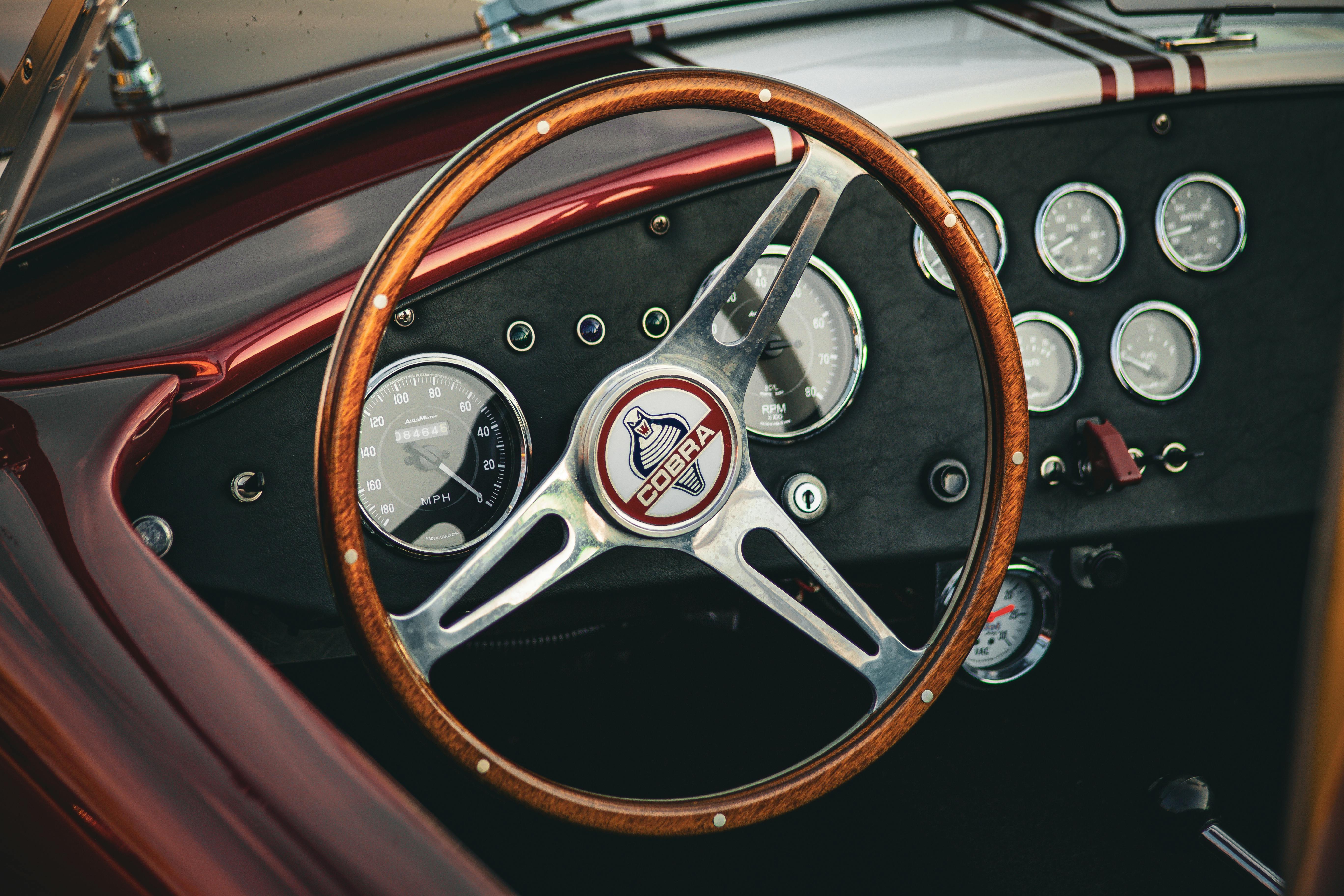 Close-up of a vintage car dashboard featuring a classic wood steering wheel and dials.