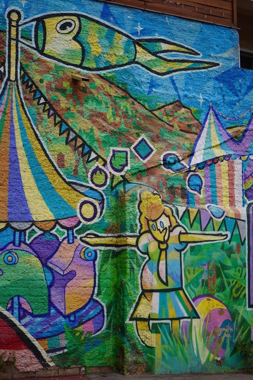 Painted carnival scene with tents, a figure and a fish kite — photo by Sergio Fdez on Pexels