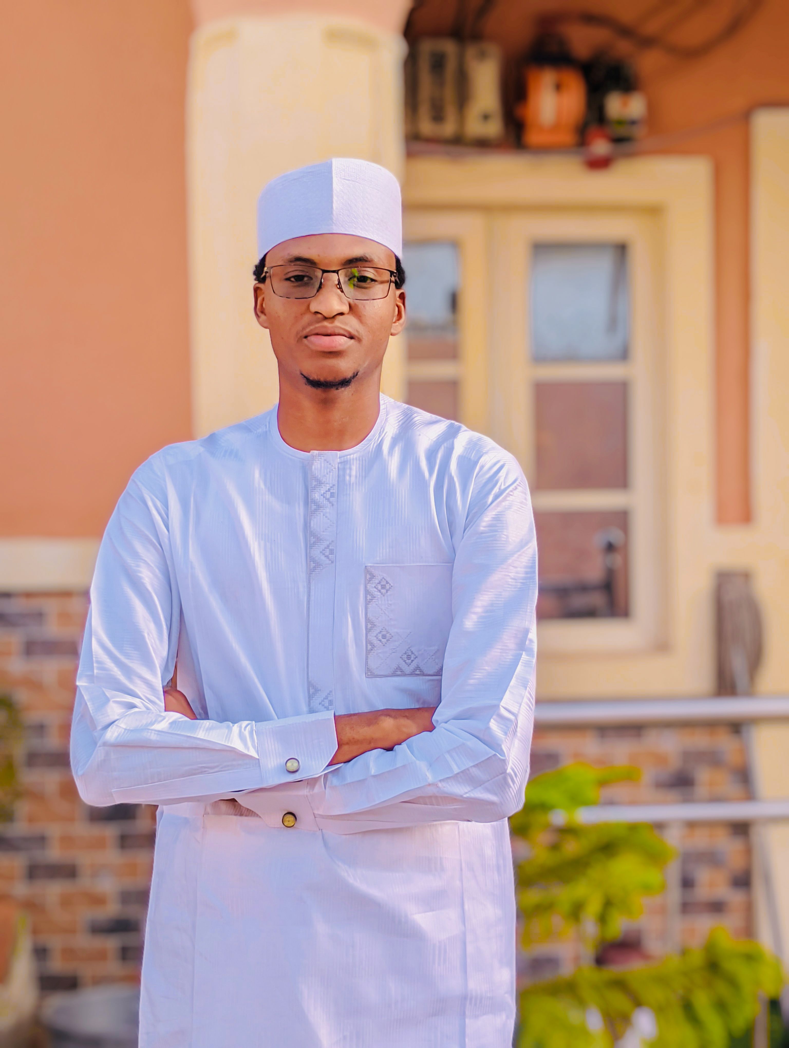 Portrait of a confident man in traditional attire standing outdoors in front of a building.