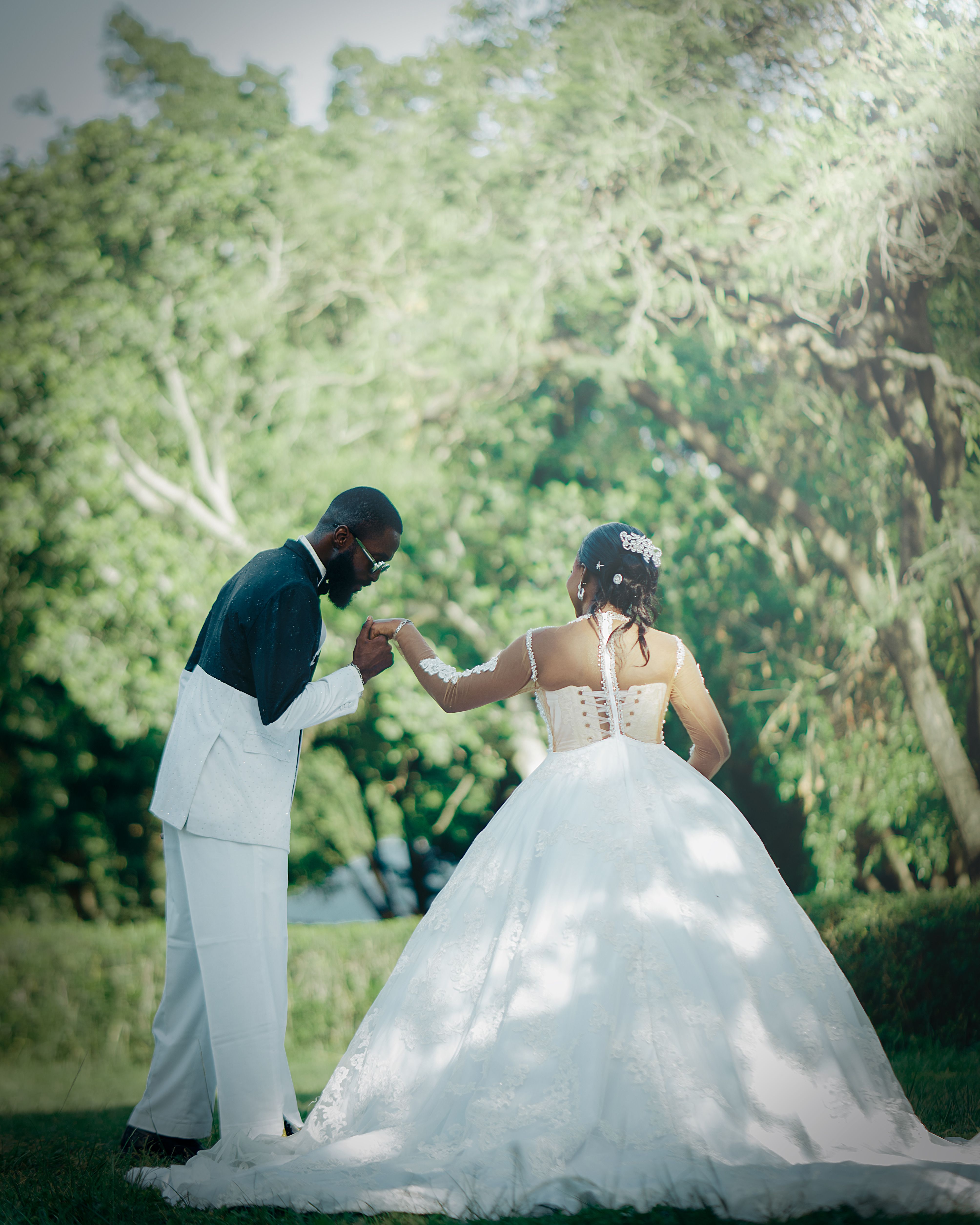 Bride and groom share a tender dance in a verdant outdoor setting, capturing a moment of love.