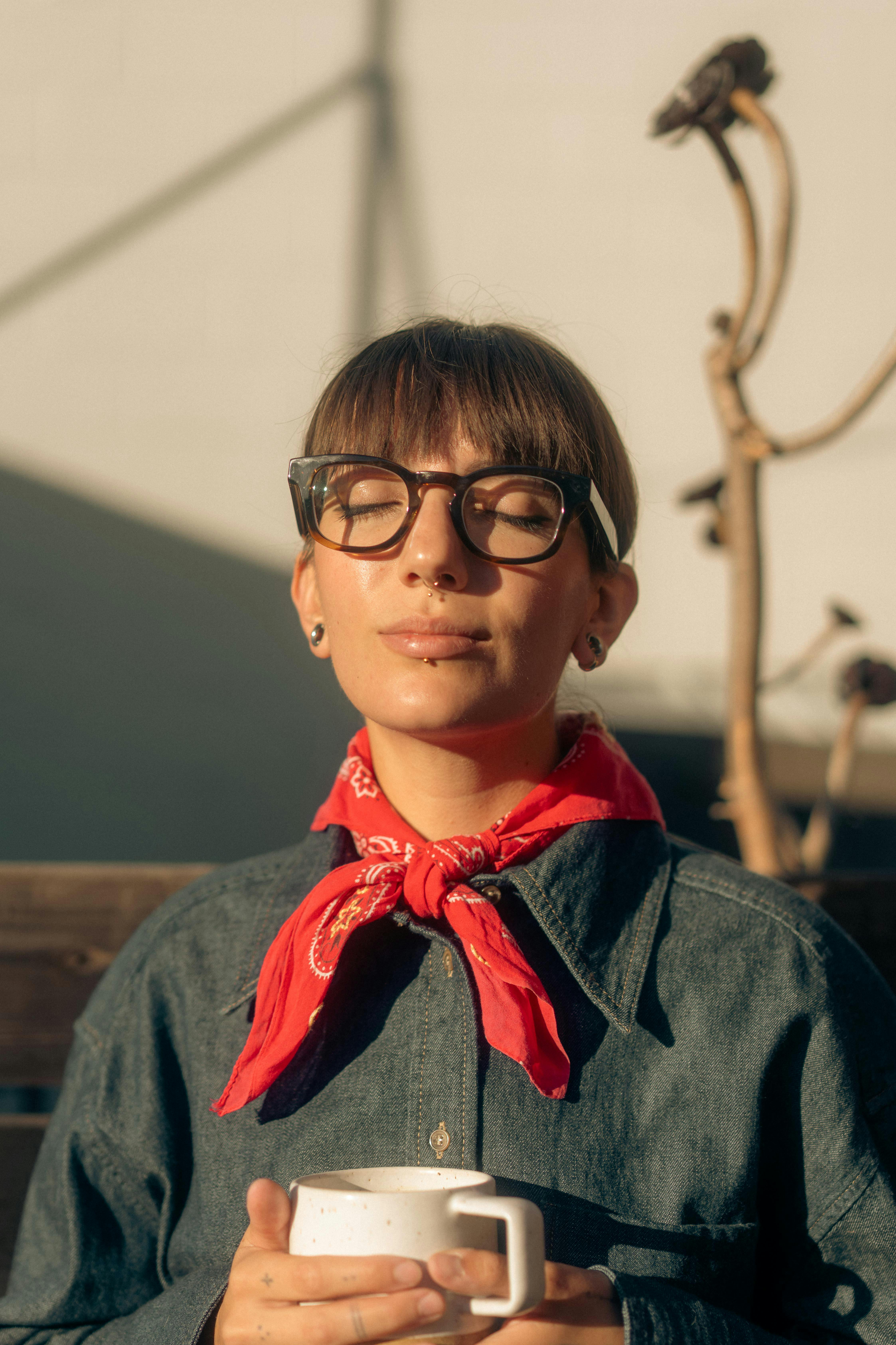 Miễn phí Chân dung một người phụ nữ đang tắm nắng trong khi cầm một tách cà phê, toát lên vẻ thanh thản và thư thái. Ảnh lưu trữ