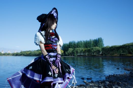 Cosplay enthusiast by serene lake in Zhangye, China, under bright blue sky.
