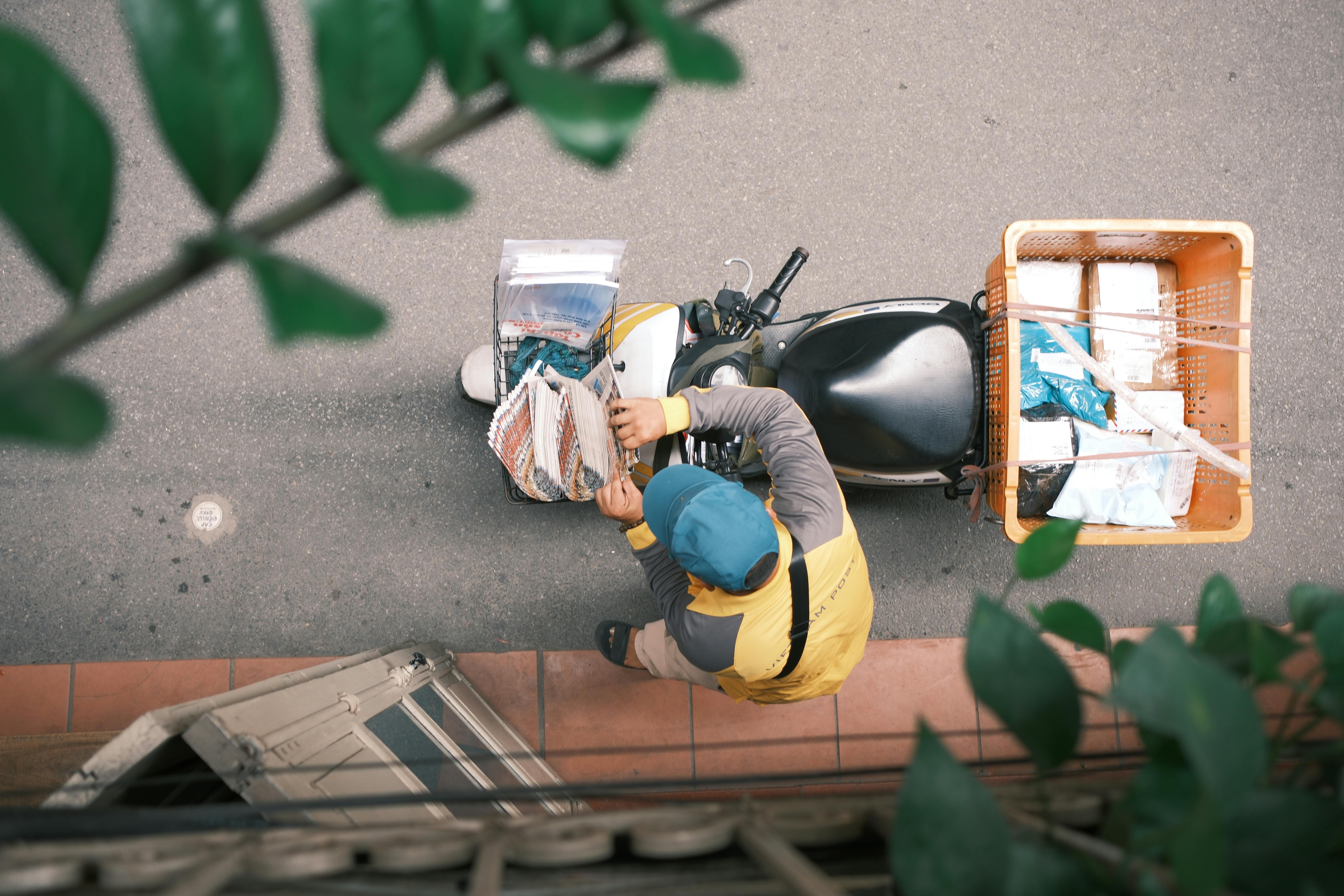 Courier on a motorcycle delivering packages in a vibrant Hong Kong street.