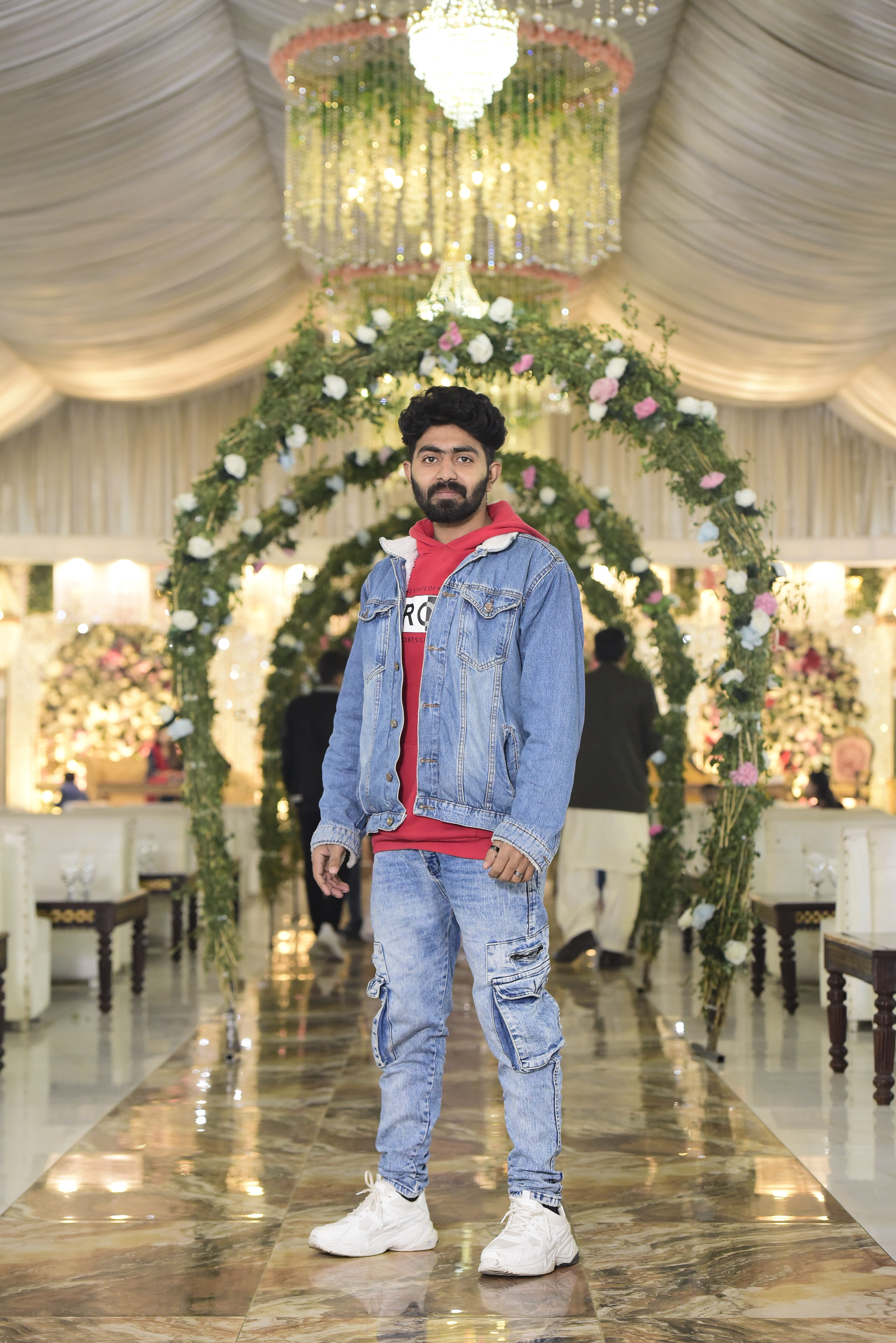 Young man in denim jacket at a beautifully decorated event in Lahore, Pakistan.