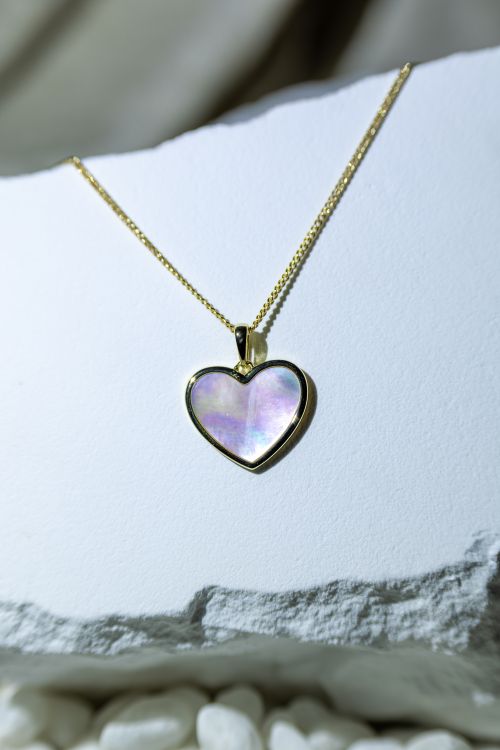 Free Elegantly crafted heart-shaped pendant with mother of pearl in a gold setting, perfect for gifting. Stock Photo