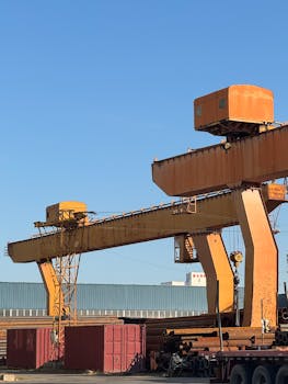 Photo by Shuaizhi Tian Large industrial cranes in a sunny outdoor setting, conveying industry and construction themes.