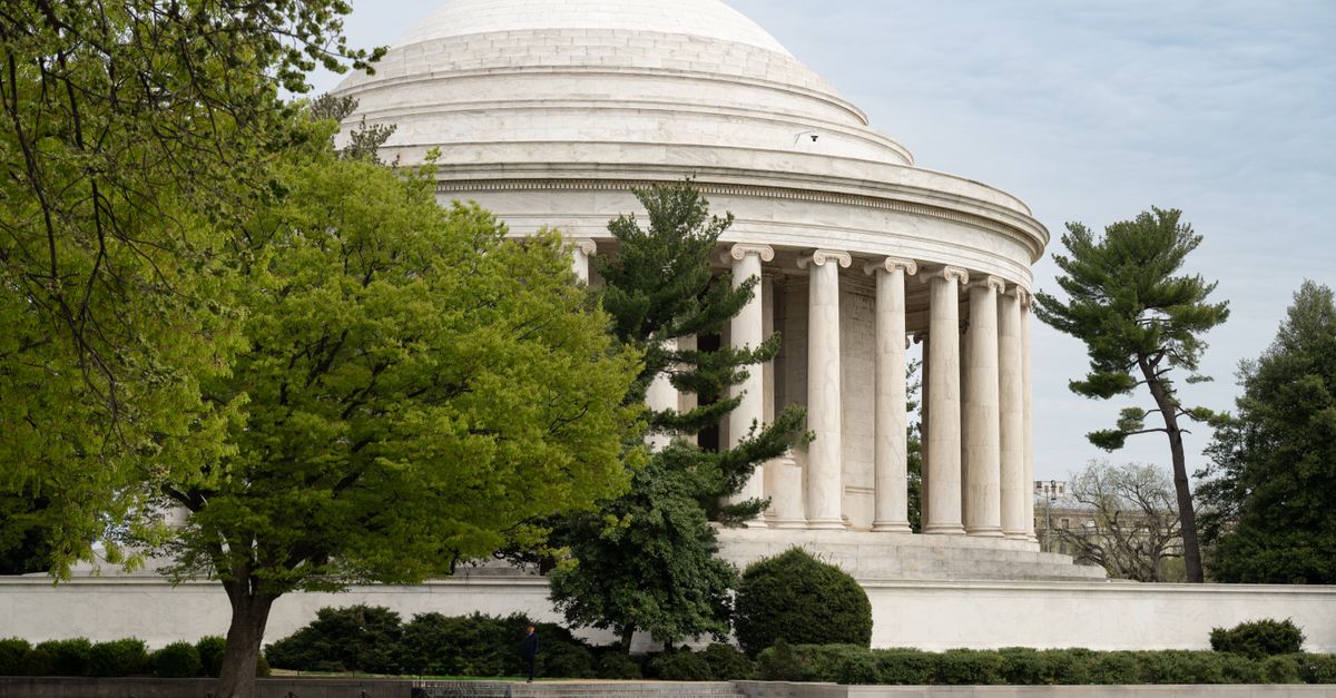 A view of the Jefferson Memorial through lush trees in Washington, D.C., showcasing classic architecture.